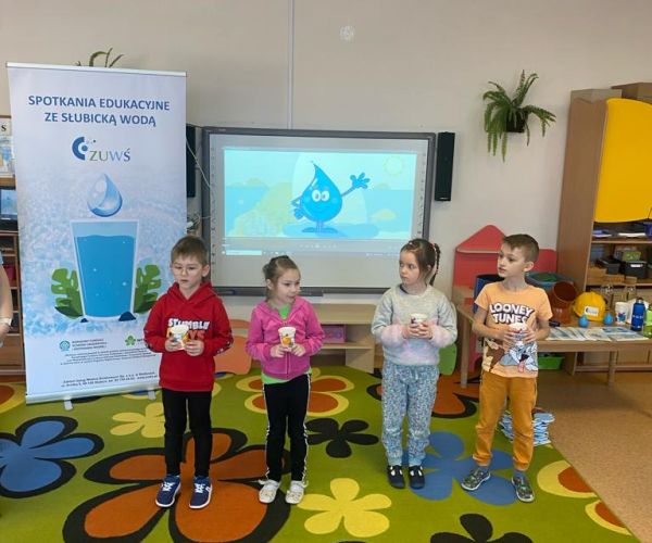 Dzieci na warsztatach pijące wodę z kubków. 