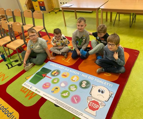 Dzieci siedzące przy ułożonym obrazie z puzzli. 