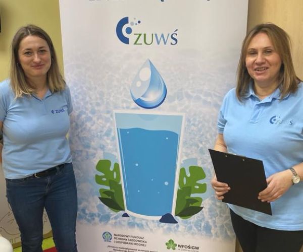 Pracownice ZUWŚ Sp. z o.o. na tle rollupa z informacją o projekcie.