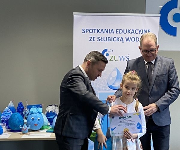 Prezes ZUWŚ i burmistrz Słubic z laureatką konkursu na tle rollupa z napisem: Spotkania ze słubicką wodą.